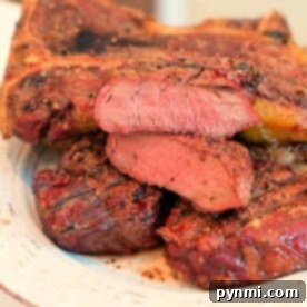 A plate featuring several slices of smoked steak at 250 degrees, showcasing a perfect sear on the outside with a tender, pink interior. The seasoned steak is artfully arranged on a pristine white plate.