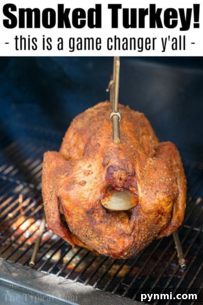 A whole smoked turkey, boasting crispy, golden-brown skin with visible seasoning, hangs on a metal hook inside a smoker. Text at the top reads, Smoked Turkey! - This is the best smoked turkey—a game changer y'all!