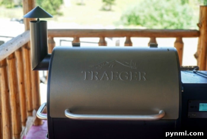 A Traeger grill on a wooden deck, with a visible chimney and engraved logo on the lid, awaits the best meats to smoke for your next flavorful feast.