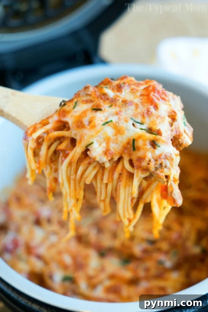 Cheesy Ninja Foodi spaghetti: The ultimate one-pot dinner using pressure cooker and air fryer for baked spaghetti perfection. #ninjafoodi #ninjafoodirecipes #bakedspaghetti #spaghetti #cheesy #airfryer #pressurecooker #aircrisp #pasta Cheesy Ninja Foodi spaghetti with tender noodles and melted cheese on top, ready to be served from the Ninja Foodi pot.