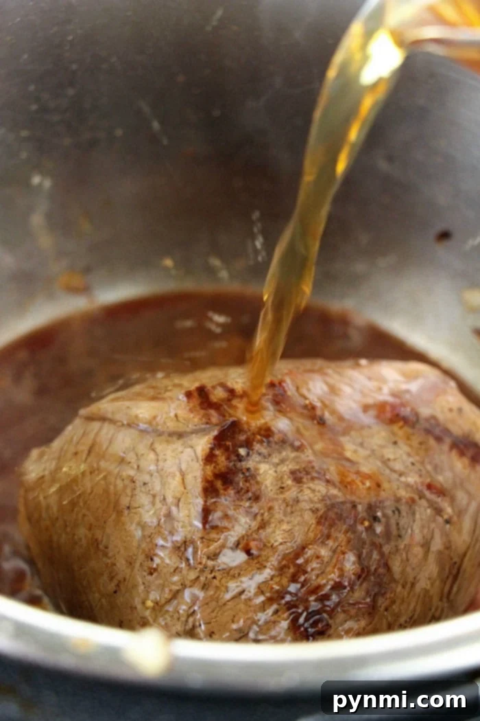 Succulent Ninja Foodi Roast Beef 6 A frozen roast being placed on a trivet inside a pressure cooker with liquid below.