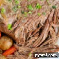A close-up of a Ninja Foodi pot roast with carrots and potatoes, garnished with herbs.