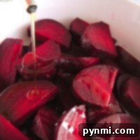 Chopped red beets in a bowl, freshly cooked to perfection using an Instant Pot, are being drizzled with oil.
