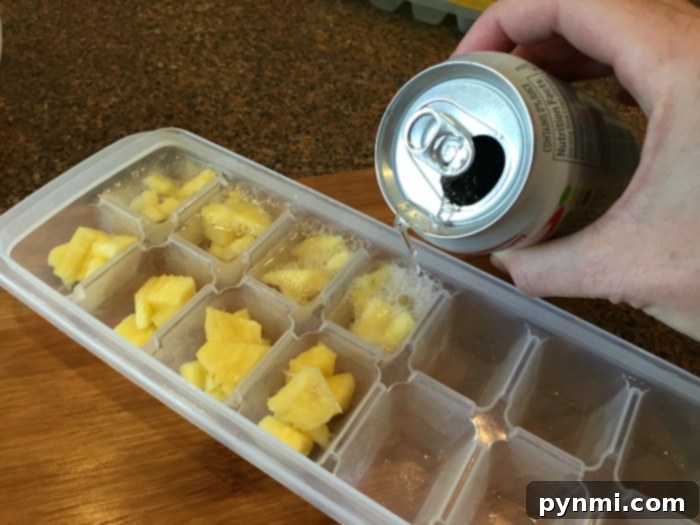 Pineapple chunks frozen into ice cubes, perfect for chilling and flavoring summer drinks.