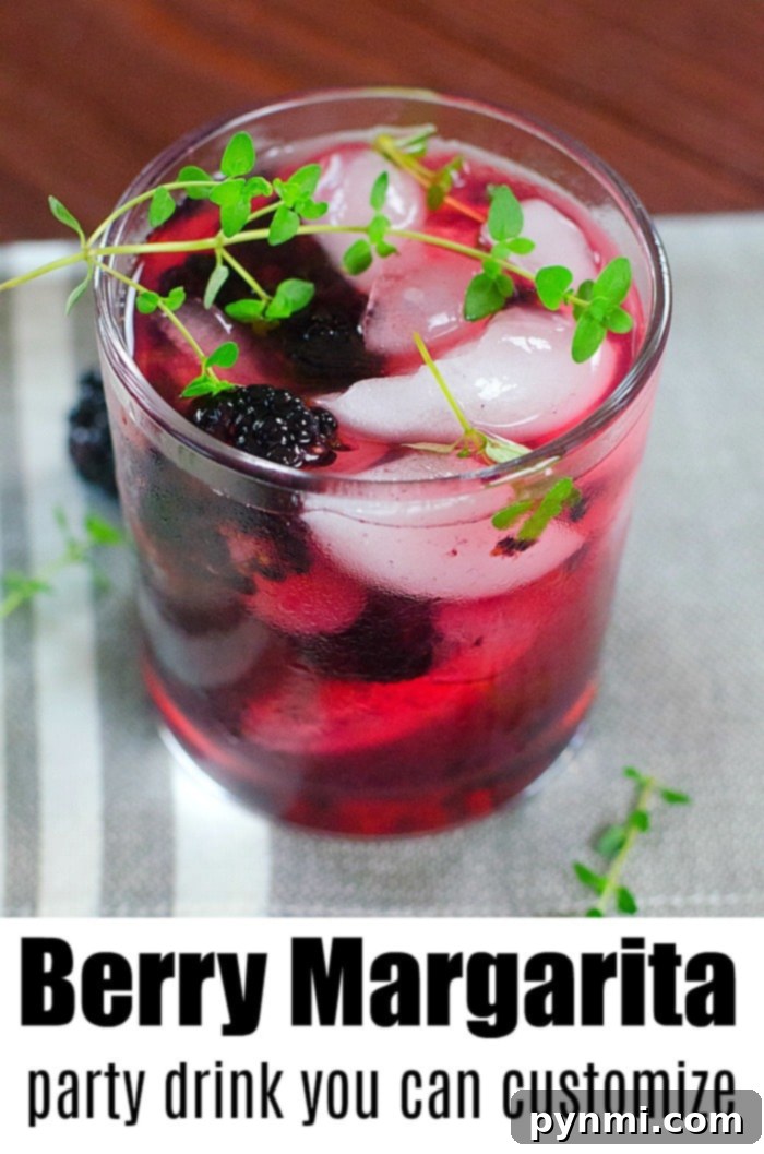 A berry margarita with fresh berries and a lime wedge, in a salt-rimmed glass.