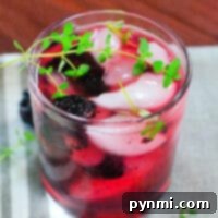 A refreshing summer cocktail garnished with fresh berries and thyme.