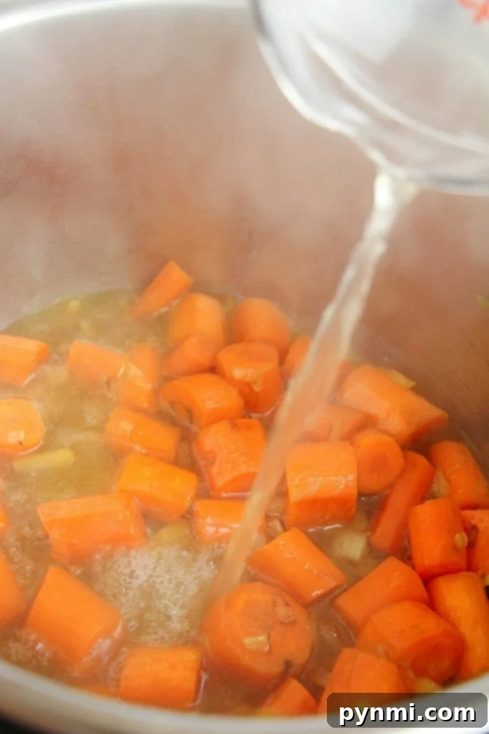 Water being poured into an Instant Pot where chopped carrots simmer in broth.