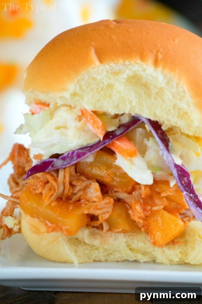 A delightful pulled pork sandwich with fresh coleslaw and a slice of grilled pineapple, perfectly arranged for your July gatherings, crafted effortlessly with Instant Pot magic.