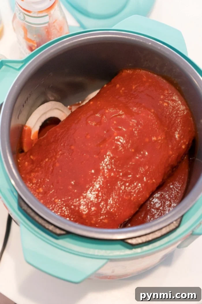 chuck roast topped with sauce sits deliciously inside a pressure cooker on the countertop, reminiscent of comforting instant pot beef roast recipe.