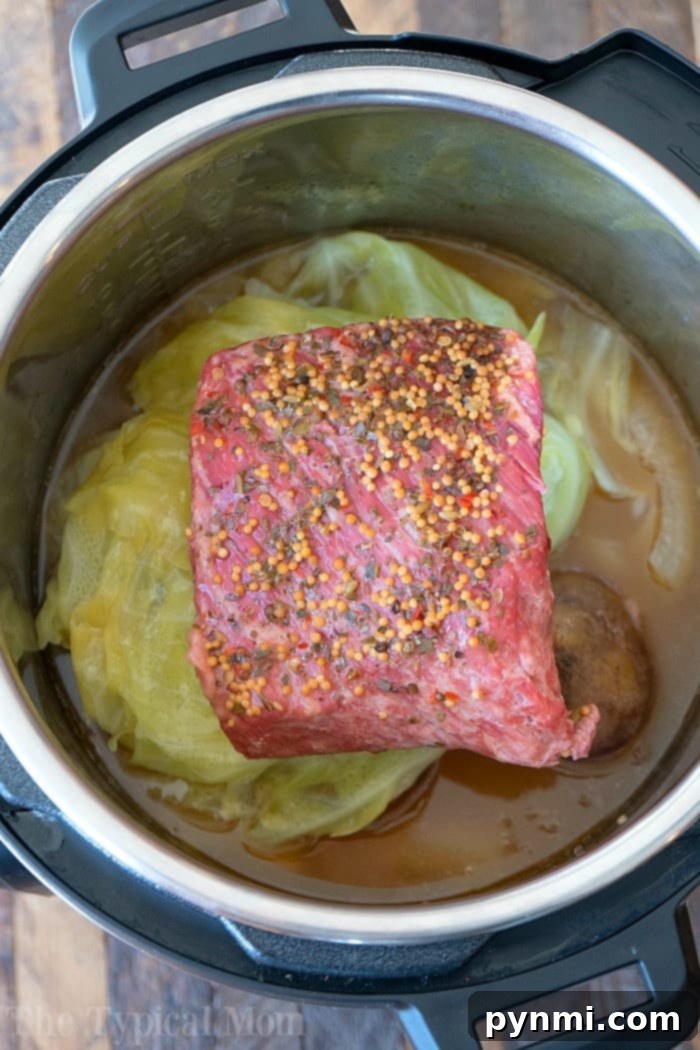 A hearty plate of easy Instant Pot corned beef and cabbage, featuring tender corned beef slices, perfectly cooked cabbage, potatoes, and carrots, garnished with fresh parsley.