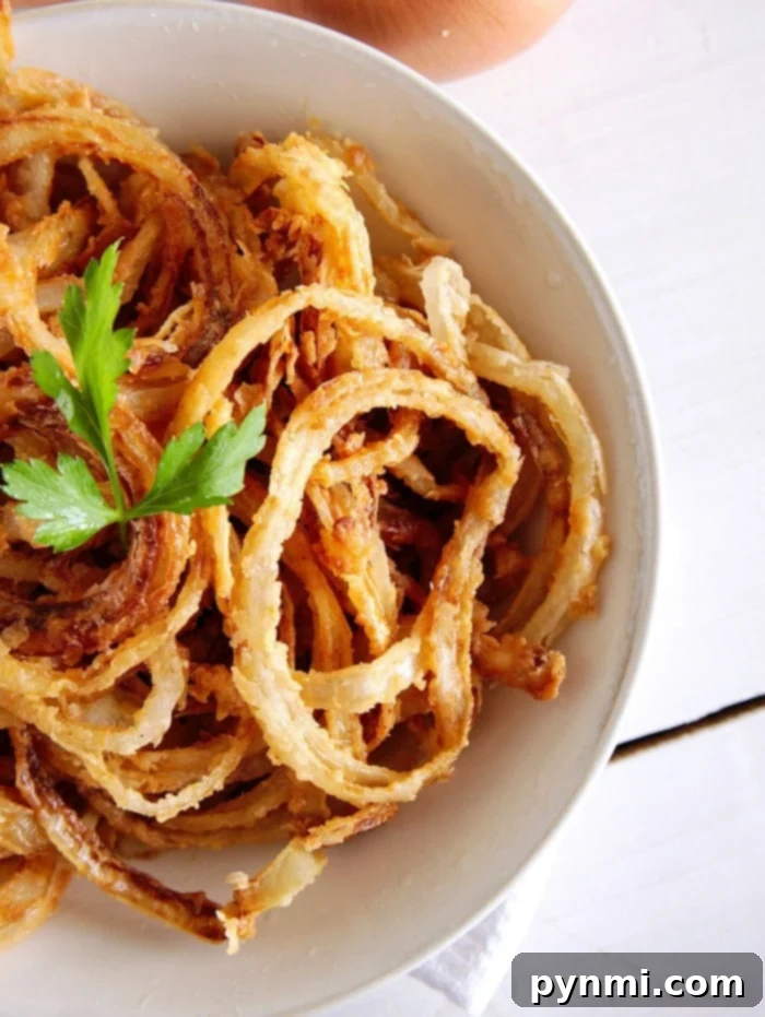 Crispy Fried Onions: The Perfect Topping or Snack! A bowl of crispy fried onion rings garnished with fresh parsley, ready to serve.