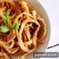 A bowl of crispy fried onion rings garnished with fresh parsley.