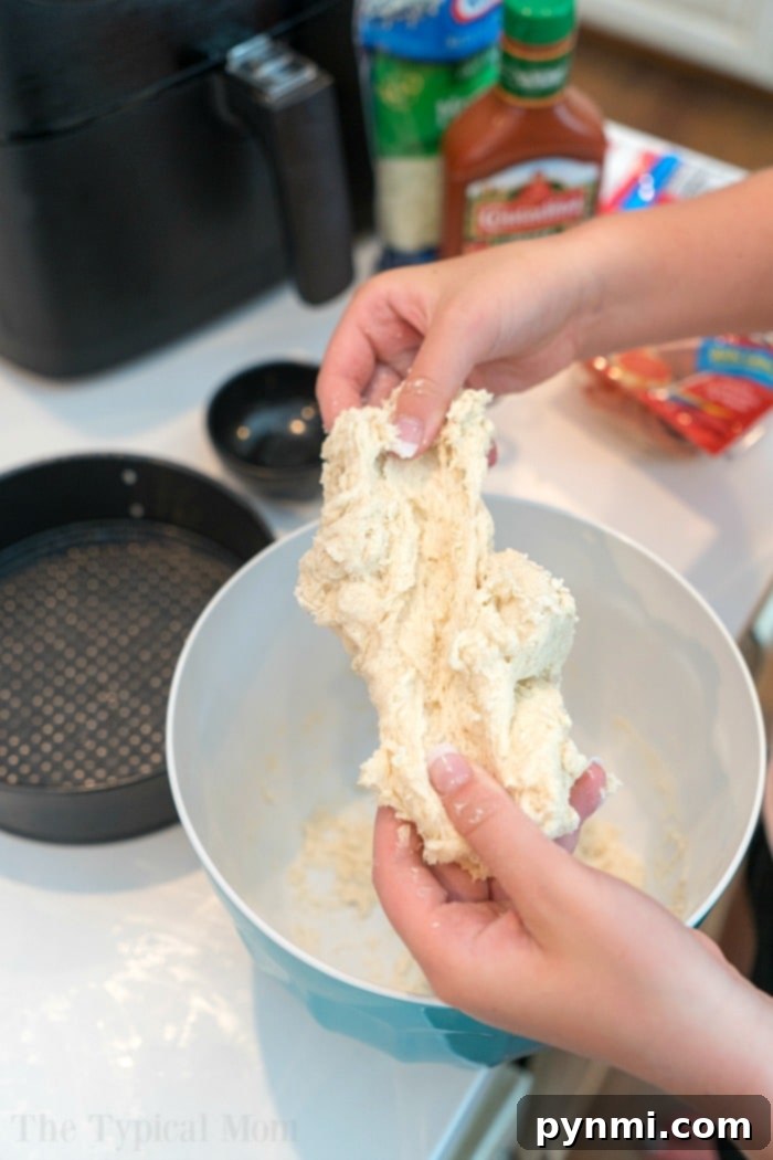 Pizza dough pressed into a round pan, ready for air frying.