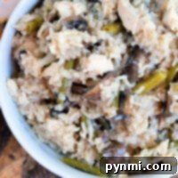 A creamy pressure cooker chicken mushroom casserole with rice and green beans sits invitingly on a wooden surface.