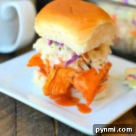 A delicious crockpot buffalo chicken slider with coleslaw graces a square white plate.
