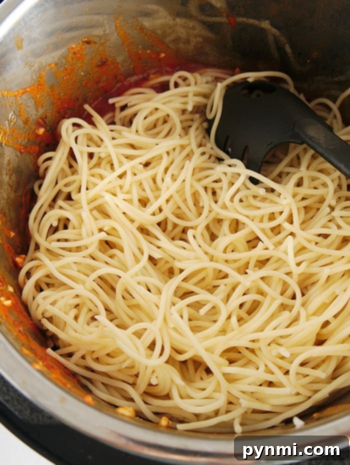 Instant Pot Chicken Parmesan Perfection 8 Spaghetti in a pot with tomato sauce remnants and a black pasta serving spoon, reminiscent of a quick instant pot chicken parmesan evening delight.