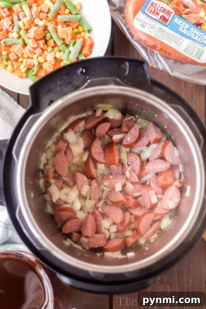 Instant Pot sausage and rice is so good! A cheesy casserole packed with smoked sausage, tender rice and vegetables cooked all in one pot in no time at all. #instantpot #instantpotrecipes #sausage #rice #casserole #cheesy #pressurecooker #ninjafoodi A hearty Instant Pot sausage and rice casserole, rich with cheesy goodness, ready to be served.