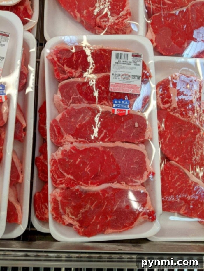 A raw steak beautifully seasoned, prepared for grilling in the Ninja Foodi.