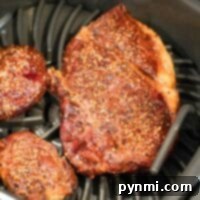 Two seasoned steaks are being expertly cooked in the Ninja Foodi Grills air fryer basket, ensuring juicy perfection with every bite.