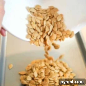 Pumpkin seeds being poured from a white bowl onto a baking tray, ready to be transformed into a crispy snack. Discover how long to bake pumpkin seeds at 350 degrees for the perfect crunch.