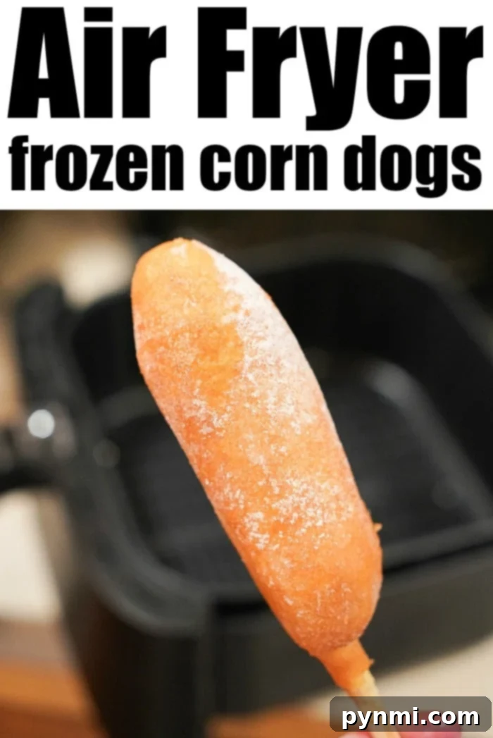 Close-up of a hand pulling a perfectly golden-brown air-fried corn dog from the air fryer basket