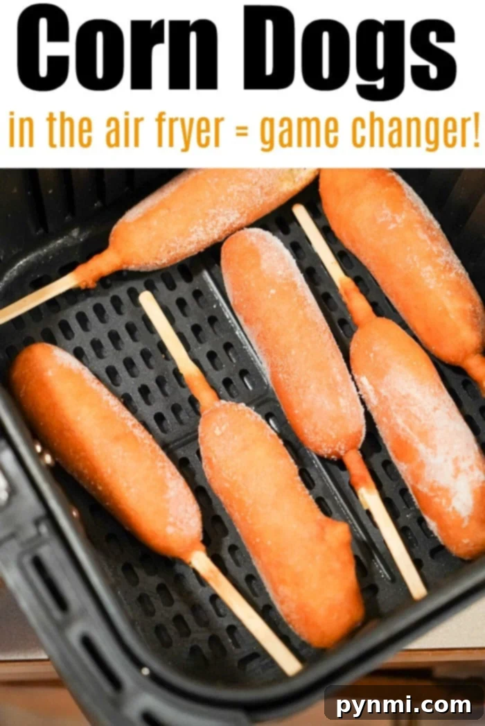 An assortment of various frozen foods, including corn dogs, arranged in an air fryer basket, ready to cook