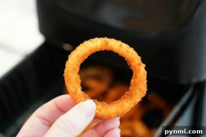Perfectly Crispy Air Fryer Frozen Onion Rings 5 Close-up of golden brown, perfectly crispy air fryer onion rings in a serving dish, highlighting their delicious texture.