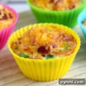 A close-up of colorful cupcake molds filled with air fryer egg bites on a wooden surface showcases the deliciously baked muffins.