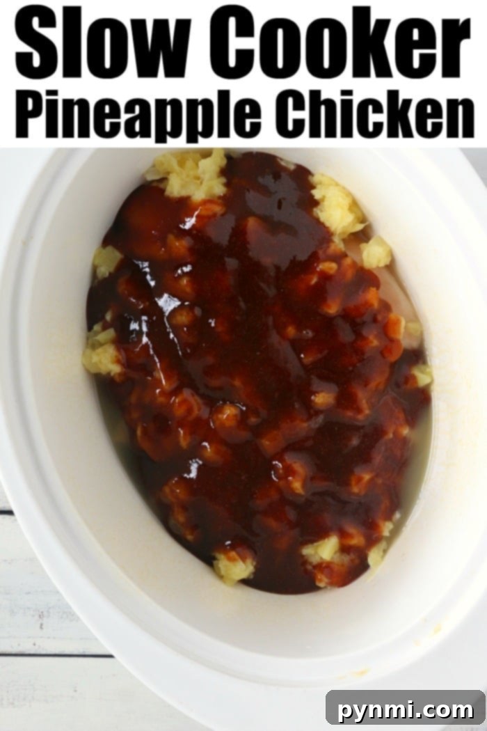 Crockpot Hawaiian chicken has only 5 ingredients! Some call this slow cooker pineapple chicken because it's sweet with a bit of a barbecue kick to it! #crockpotrecipeseasy #crockpotrecipes #slowcookerrecipes #hawaiianchicken #pineapplechicken A close-up shot of a slow cooker filled with Crockpot pineapple chicken, bubbling gently in its sweet and savory sauce, garnished with fresh pineapple chunks, indicating a meal perfectly cooked and ready to be served.