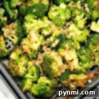 Crispy Air Fryer Broccoli 6 A close-up shot reveals the vibrant green of perfectly roasted broccoli in an air fryer basket, showcasing the crispy texture and delightful char achieved with ease.