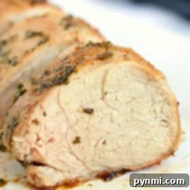 Close-up of sliced roasted pork loin, seasoned with herbs and cooked to perfection in an air fryer, showcasing a juicy and tender texture.