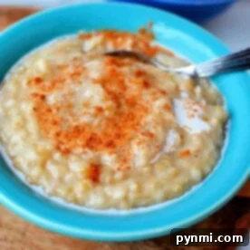 A blue bowl of creamy slow cooker steel cut oats is topped with cinnamon and milk, with a spoon resting inside.