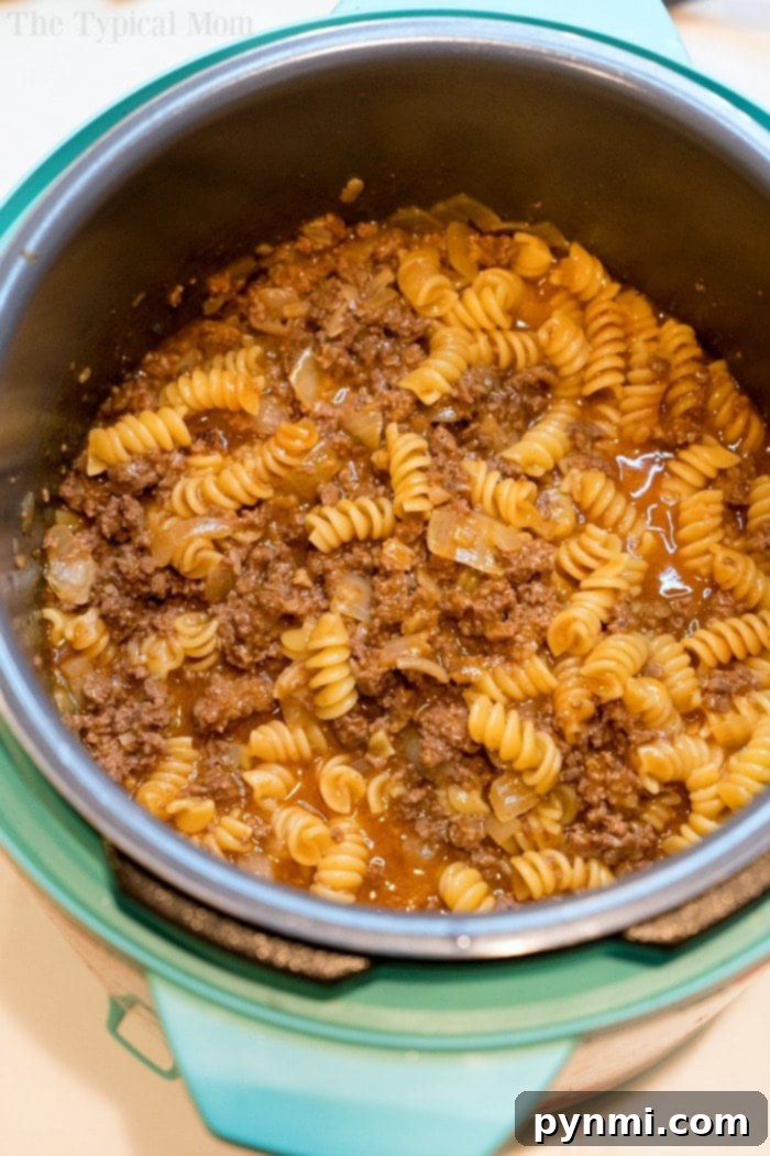 Instant Pot enchilada pasta is a creamy pasta with ground beef or sausage and all the Mexican flavors you love. Cooked in 4 minutes, you'll want seconds. #instantpotrecipeseasy #instantpot #enchiladacasserole #instantpotpasta #enchiladapasta #thetypicalmom A close-up of a serving of Instant Pot enchilada casserole, showcasing its creamy texture.