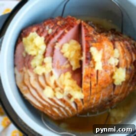 A spiral-cut ham with pineapple chunks and juice in a Ninja Foodi, ready to be cooked to perfection.