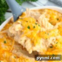 Creamy cheesy chicken rotini pasta, cooked to perfection in an instant pot, garnished with herbs and served from a white bowl.