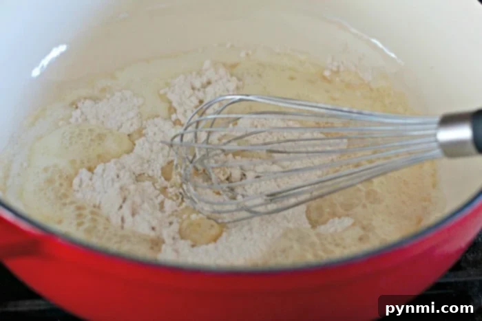 Close-up of butter melting and flour being whisked to create a perfect roux for cheese sauce.