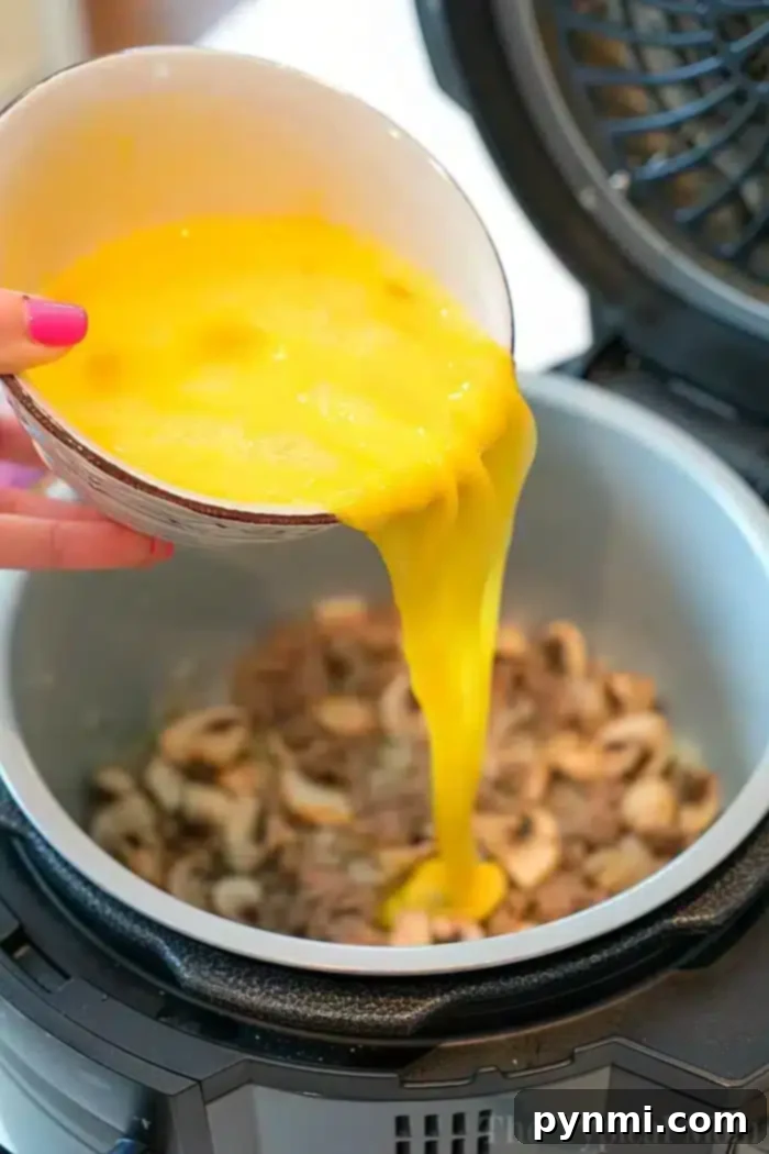 Air Fryer Breakfast Delights 5 A bowl of beaten eggs is being poured into an electric pressure cooker containing sautéed mushrooms, creating a delightful breakfast dish that's as effortless as using an air fryer.
