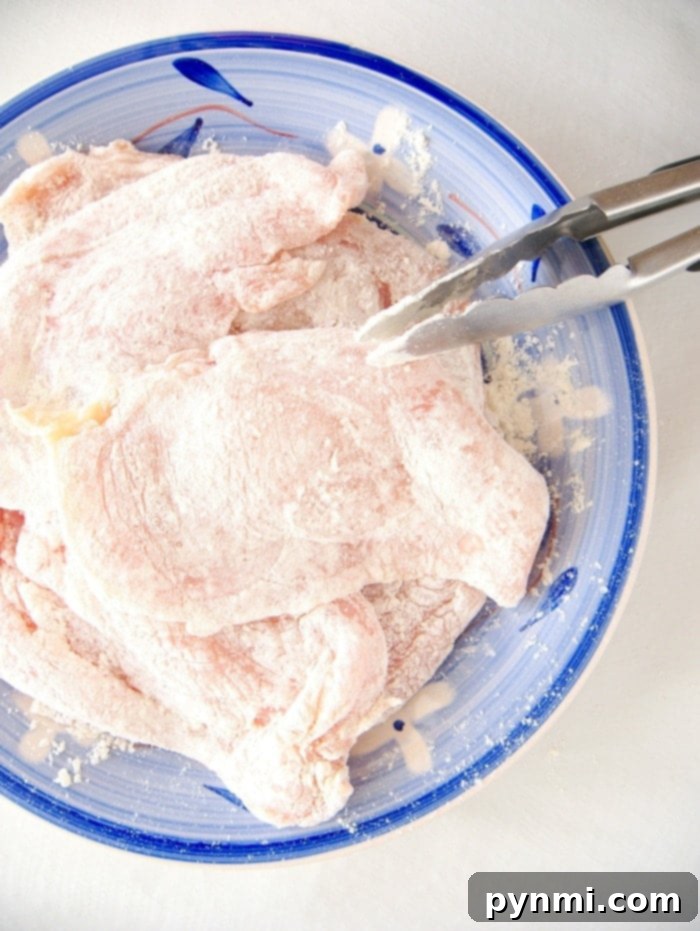 Raw chicken cutlet pieces, perfectly coated in seasoned flour, ready for sautéing for a quick chicken marsala, displayed on a blue plate.