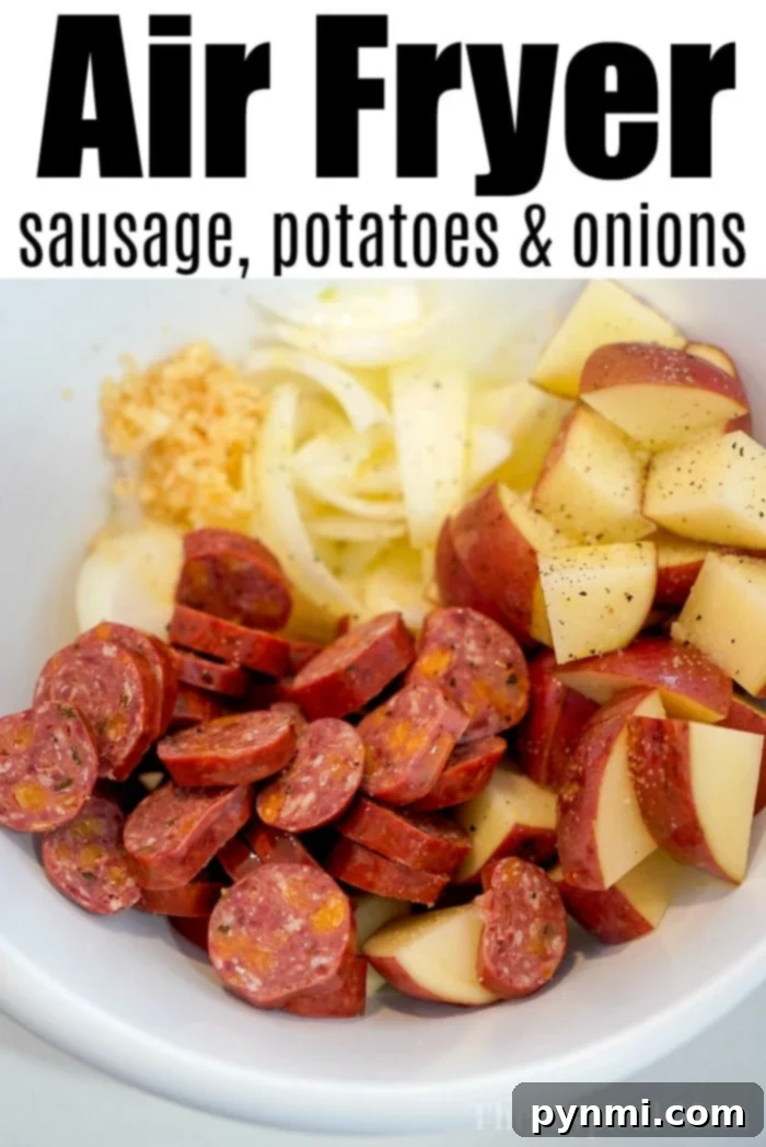 Air fryer basket filled with cooked sausage, potatoes, and onions