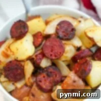 A bowl of air-fried sausage with crispy roasted potatoes and caramelized onions.