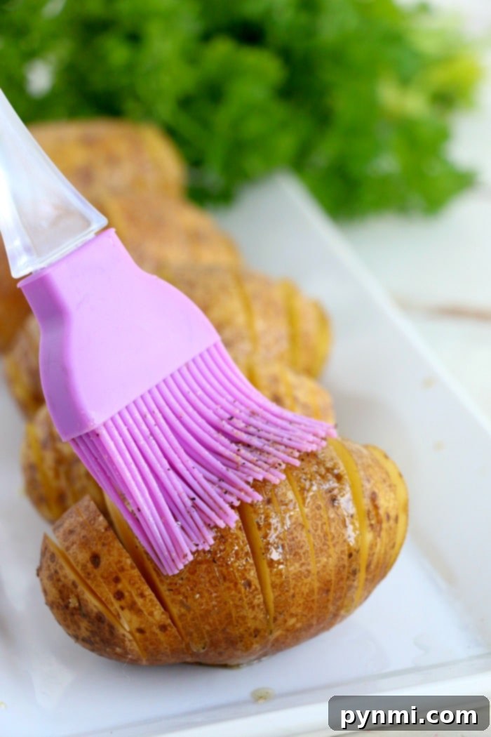 Best hasselback potatoes are little bites of heaven! Crispy baked potatoes loaded with cheese and bacon and then topped with sour cream and chives. #airfryer #ninjafoodi #foodi #hasselbackpotatoes #bakedpotatoes #airfryerrecipes A beautifully prepared Hasselback potato with fanned out slices.