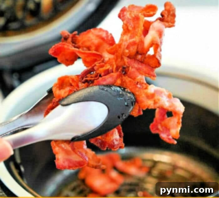 Crispy air fryer bacon slices on a white plate with fresh herbs, showcasing the golden perfection achieved in an air fryer.
