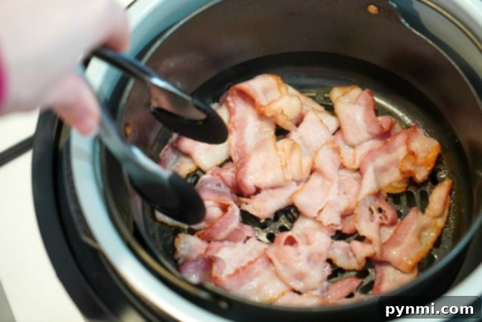 Close-up of raw bacon strips perfectly arranged in a Ninja Foodi air fryer basket, ready for cooking to achieve ultimate crispiness.