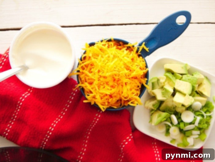 A close-up of various vibrant toppings for Mexican dishes: sliced avocados, fresh green cilantro, and a bowl of creamy sour cream, ready to adorn your favorite meal.