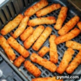 Golden, crispy air fryer fish sticks arranged in a single layer inside an open basket, ready to enjoy.