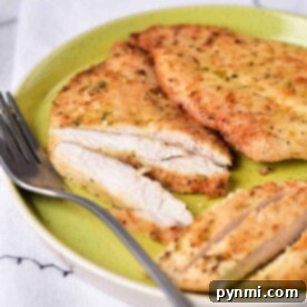 Grilled chicken breast slices on a green plate with a fork on the side, showcasing the perfect result of mastering how to cook chicken in an air fryer.
