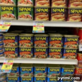 Cans of SPAM, perfect for your air fryer recipes, with various flavors and prices are displayed on grocery store shelves.