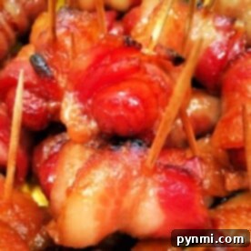 Close-up image of Bacon Wrapped Smokies secured with toothpicks. The bacon is cooked to a crispy, golden-brown finish in the Ninja Foodi. The appetizers are closely packed, showcasing the texture and color variation from the caramelized and well-cooked bacon.
