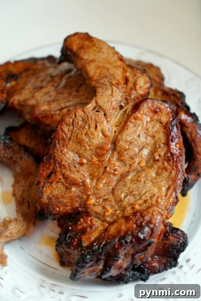 Thick slices of air-fried teriyaki roast beef, beautifully caramelized on the edges and juicy in the center, resting on a cutting board, ready to be served.