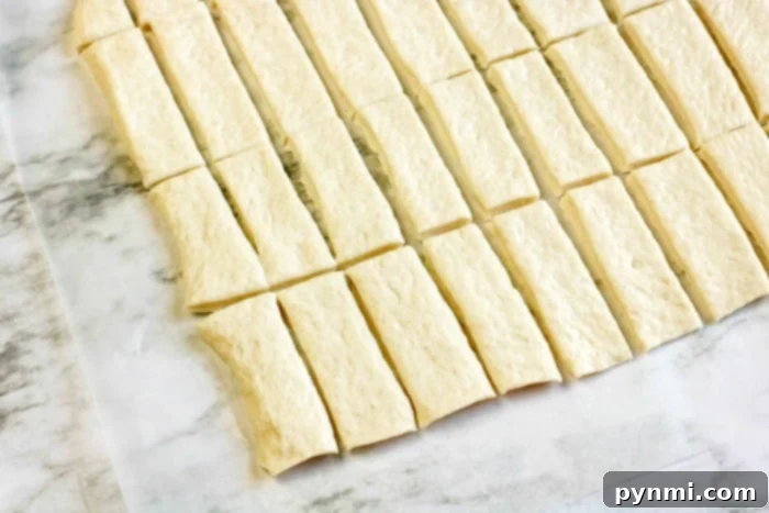 Unrolled refrigerated pizza dough, perfectly prepared for slicing into strips and wrapping around smokies.